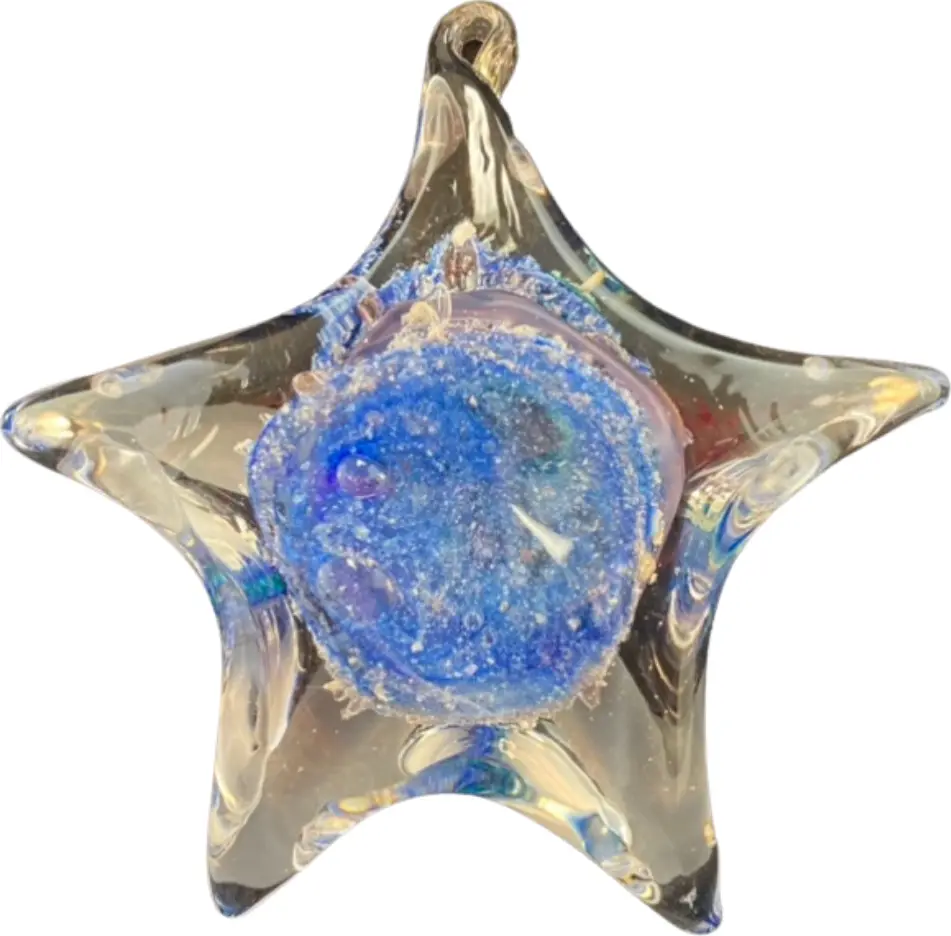 A clear glass star with a disc of blue glass and ashes at its heart