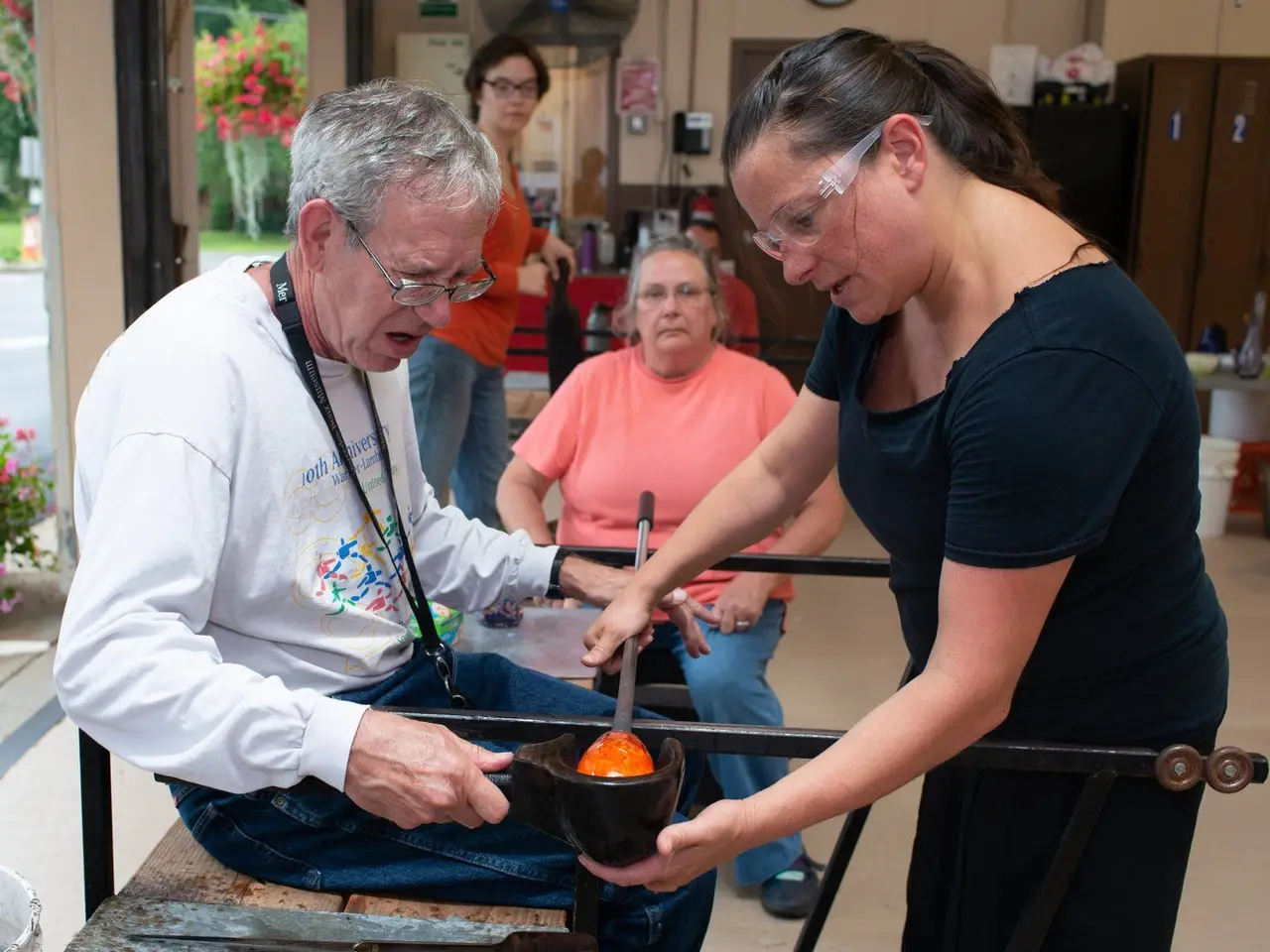 Instructor Michelle guides an older student shaping a bowl