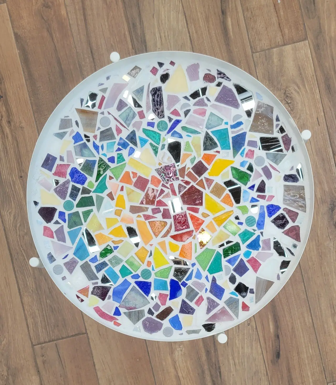 A round mosaic tabletop in rainbow shards of glass