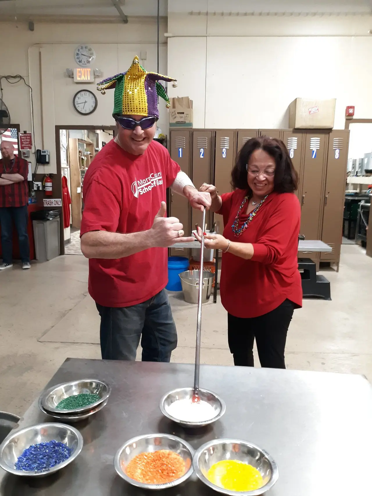 A couple in Mardi Gras beads give a thumbs-up at the bench